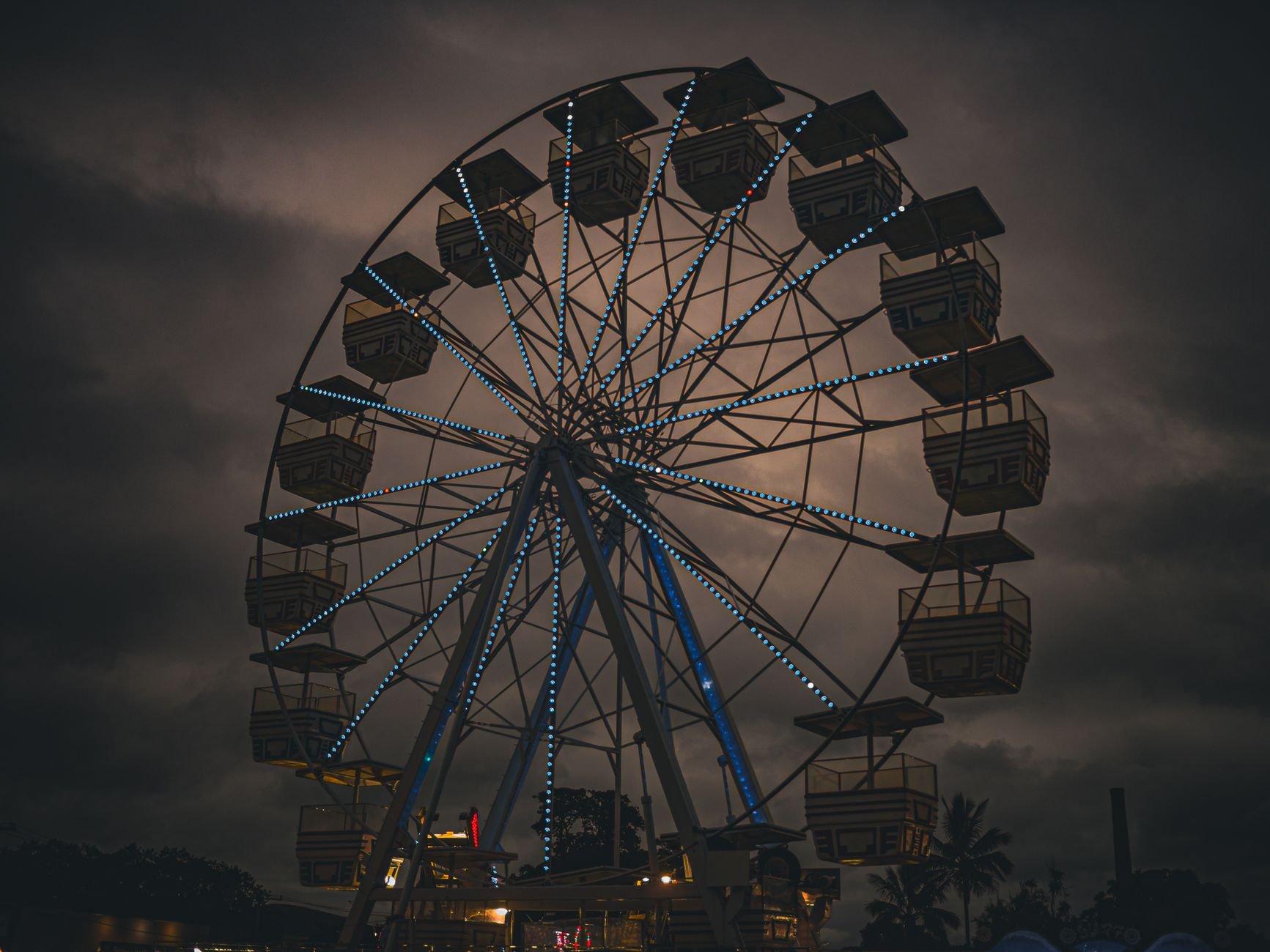 A Ferris wheel silhouetted against a dramatic dark night sky